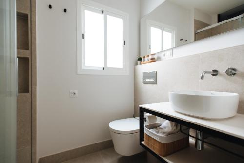 uma casa de banho com um lavatório, um WC e uma janela. em Apartamento Alameda em Sevilha