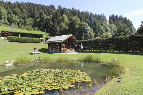 a pond with a house in the middle of a field at Le P'ti Tzi-Mé in Villars-sur-Ollon
