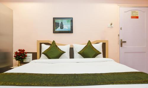 a bedroom with a large white bed with green pillows at Treebo Hillway Inn Main Market in Mahabaleshwar