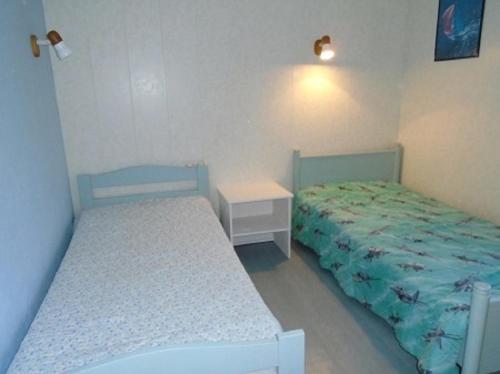 een slaapkamer met 2 bedden en een nachtkastje en een bed en een tafel bij ESCALE à FORT-BLOQUE 56 in Ploemeur