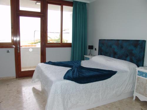 a bedroom with a bed with a blue headboard and windows at Villa Beatriz in Salobre