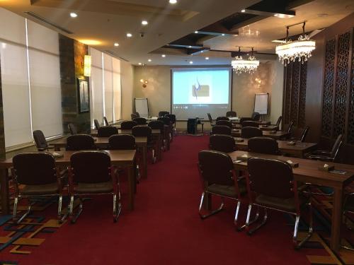 a room with tables and chairs and a projection screen at Mariana Hotel Erbil in Erbil