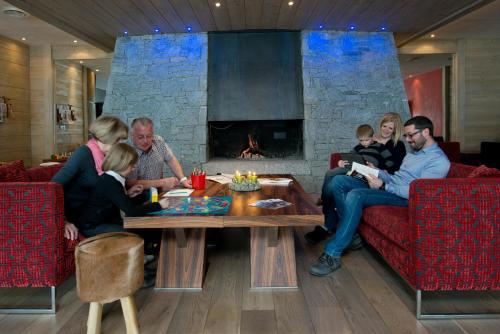 a family sitting in a living room with a fireplace at CGH Résidence Boutique Le Centaure in Flaine