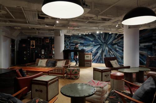a living room with tables and chairs and a piano at amba Taipei Ximending in Taipei
