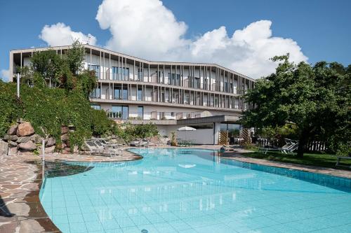 un hôtel avec une piscine en face d'un bâtiment dans l'établissement Hotel Lichtenstern, à Soprabolzano