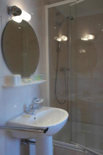 Un baño con lavabo y ducha con espejo. en Zum Goldhahn, en Amblève