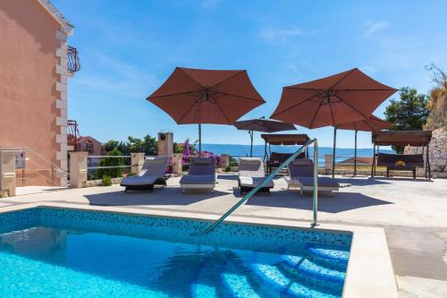 a swimming pool with chairs and umbrellas next to a pool at Bed & Breakfast Senator in Podstrana