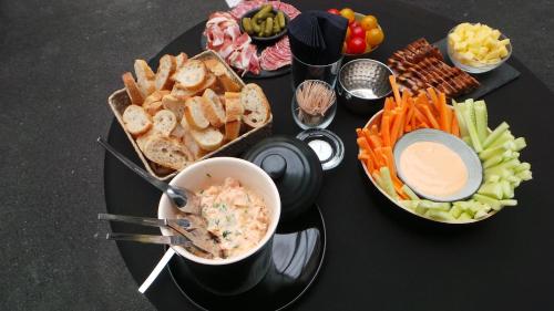 a black table topped with a plate of food with dips at Le Nouvel Hôtel in Oyonnax