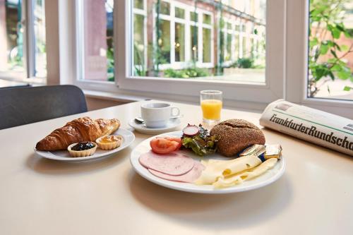 een tafel met twee borden eten en een glas sinaasappelsap bij Jugendherberge Frankfurt - Haus der Jugend in Frankfurt am Main