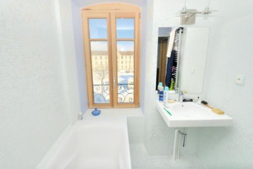a white bathroom with a sink and a window at La Drapière in Fay-sur-Lignon