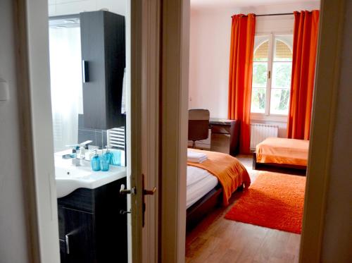 a bathroom with a sink and a bed with orange curtains at Apartment Soul in Ljubljana