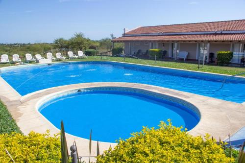 a large blue swimming pool with chairs and a house at Club Valle Termal Resort in Federación