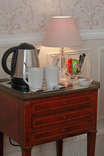 a table with two tea cups and a lamp on it at Les Chambres de Mathilde in Angers