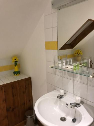 ein Badezimmer mit einem weißen Waschbecken und einem Spiegel in der Unterkunft The Pear Tree in Hook Norton