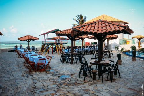 een groep tafels en stoelen met parasols op het strand bij Hotel Concha do Mar in Salinópolis