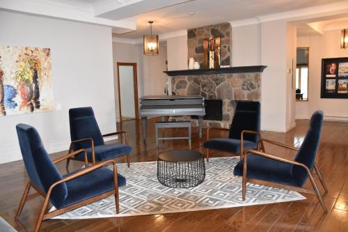a living room with a piano and chairs at Hotel Cap-aux-Pierres in L'Isle-aux-Coudres