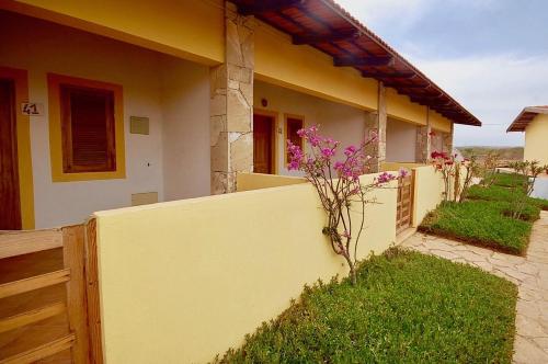 a yellow house with a fence and flowers at Villa Maris Ecolodge in Morro
