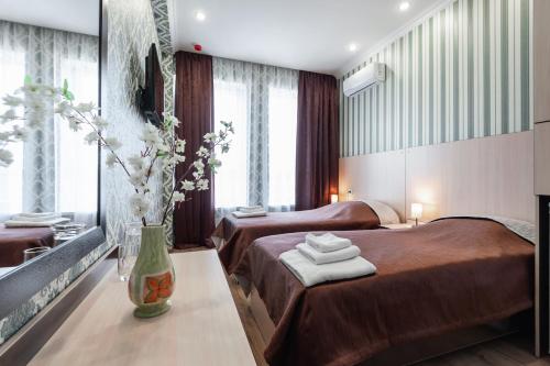 Cette chambre comprend 2 lits et un vase fleuri. dans l'établissement HOTEL PREMIER ROSTOV, à Rostov-sur-le-Don