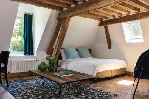 
a bedroom with a bed, a table, and a window at Le Manoir de la Plage / Adults Only in Honfleur
