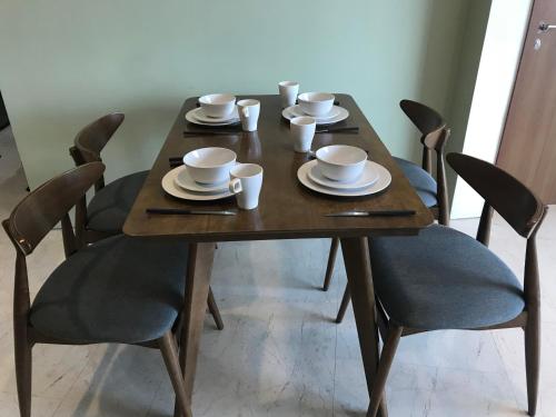 a wooden table with chairs and cups and plates on it at VORTEX SUITES KLCC by PNUT With NETFLIX in Kuala Lumpur