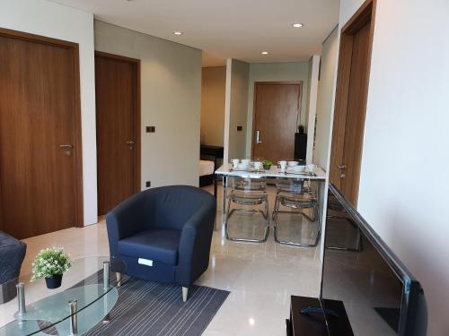a living room with a blue chair and a glass table at VORTEX SUITES KLCC by PNUT With NETFLIX in Kuala Lumpur