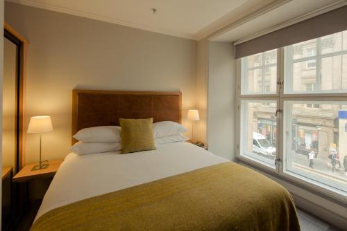 Un dormitorio con una cama grande y una ventana en PREMIER SUITES PLUS Glasgow George Square en Glasgow