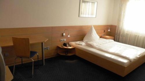 a room with a bed and a desk and a bed and a table at Hotel Habana in Aalen