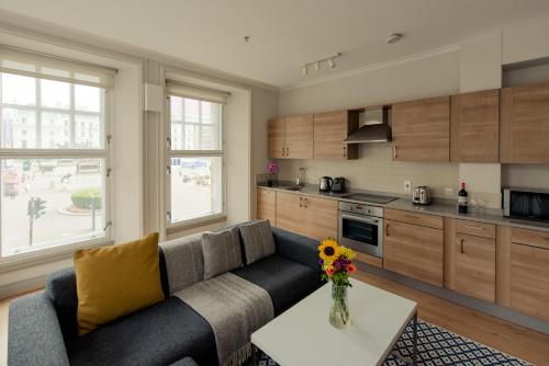 ein Wohnzimmer mit einem Sofa und einer Küche in der Unterkunft PREMIER SUITES PLUS Glasgow George Square in Glasgow