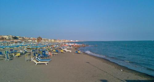 a beach with chairs and umbrellas and the ocean at AzzurRomare Flat apartment in Lido di Ostia