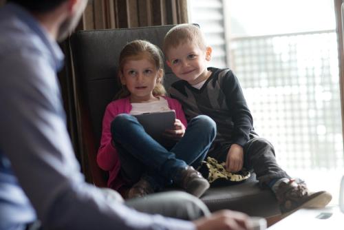 a boy and a girl sitting on a couch with a tablet at CGH Résidence Boutique Le Centaure in Flaine