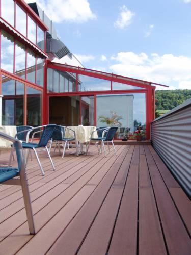 a wooden deck with chairs and a table on a house at Hotel Habana in Aalen