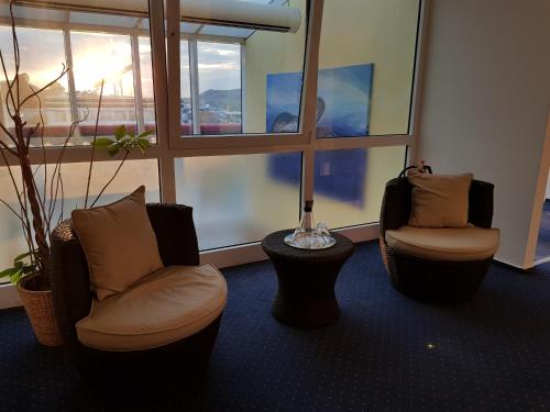 a room with two chairs and a table and windows at Hotel Habana in Aalen