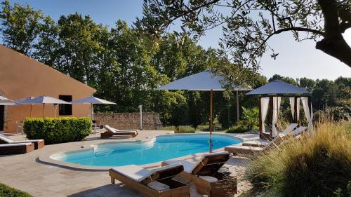 a pool with chairs and umbrellas in a yard at Domaine De Pradaous in Reillanne