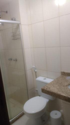 a white bathroom with a toilet and a shower at Quinta das Lagoas Residence in Itacimirim