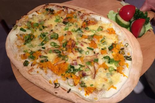 a pizza sitting on top of a wooden cutting board at Hotel Märkischer Hof in Luckenwalde