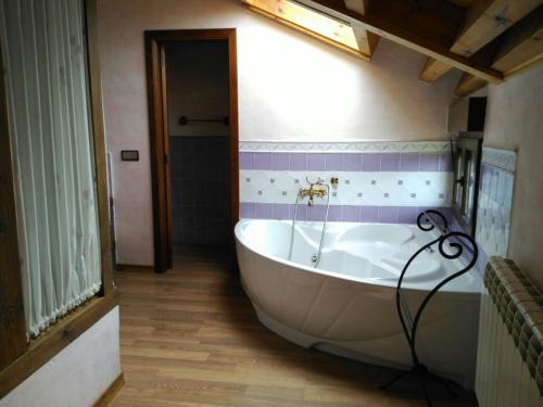baño con bañera blanca grande y azulejos morados en Casa rural Lucia, en La Horcajada