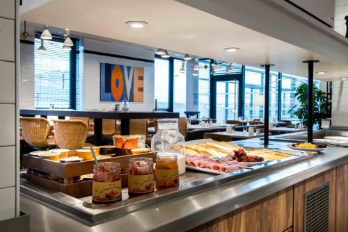 a buffet line with food on display in a restaurant at KOPSTER Hotel Lyon Groupama Stadium in Décines-Charpieu