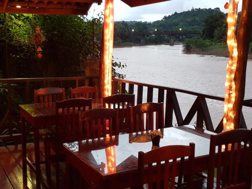 a room with chairs and a table next to a river at Thongbay Guesthouse in Luang Prabang