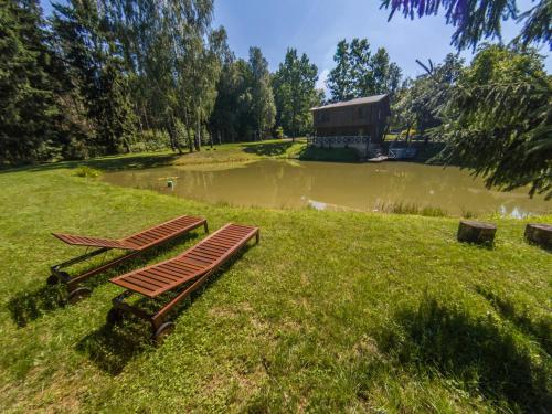 a group of benches sitting on the grass near a pond at Vila Misko Natos in Dovainonys III