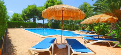 a swimming pool with two umbrellas and two lounge chairs and a swimming pool at Can Crestall in Campos