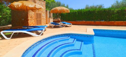 a swimming pool with two chairs and umbrellas next to at Can Crestall in Campos
