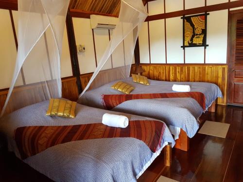 um grupo de três camas num quarto em Thongbay Guesthouse em Luang Prabang