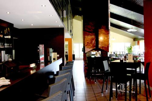 a restaurant with a bar with tables and chairs at La Berteliere, The Originals Relais in Saint-Martin-du-Vivier