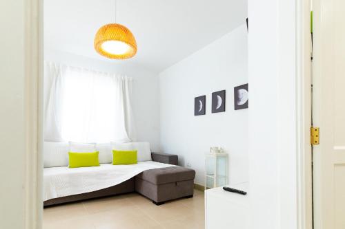 Un dormitorio con una cama con almohadas amarillas y una ventana en Lima waikiki beach, en Corralejo