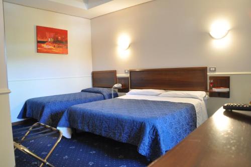 two beds in a hotel room with blue sheets at Hotel Civita in Avellino