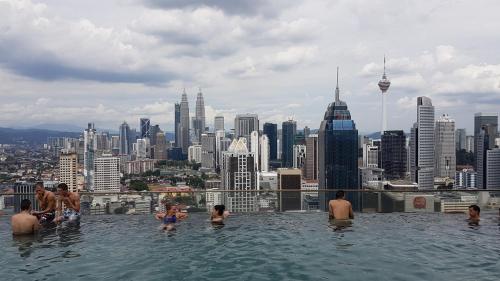 un gruppo di persone in una piscina a sfioro con vista sulla città di SkyBed Over The Sky Hostel @Regalia Suites & Residences KL a Kuala Lumpur