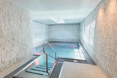 a swimming pool with a ladder in a room at ERMITAGE Wellness- & Spa-Hotel in Gstaad