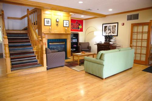 a living room with a staircase and a couch and a fireplace at Country Inn & Suites by Radisson, Bloomington-Normal West, IL in Bloomington