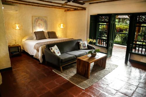 a bedroom with a bed and a couch and a table at Hacienda Bambusa in El Caimo