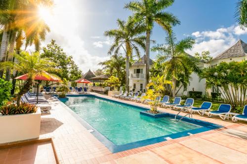 uma piscina num resort com cadeiras e palmeiras em Decameron Club Caribbean Runaway Bay, Ramada All-Inclusive Resort em Runaway Bay